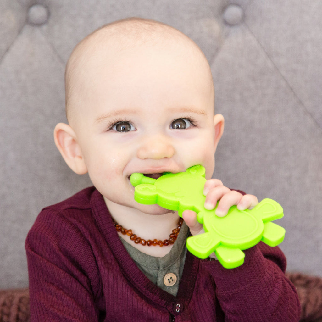 Baby smiling while chewing lime green giraffe teether