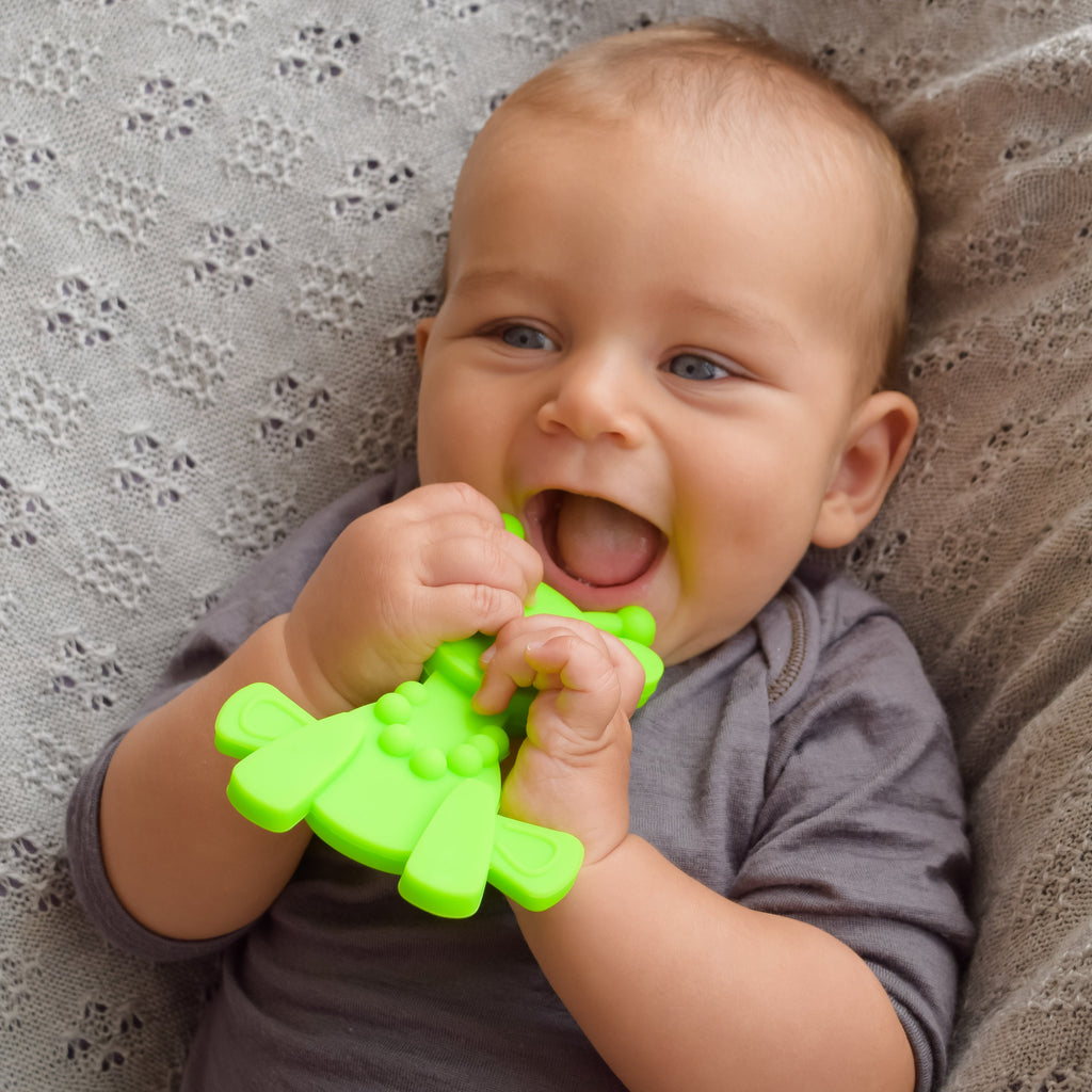 Baby chewing on lime green giraffe-shaped teething toy