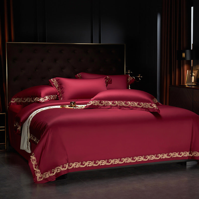 Red satin bedding set featuring an embroidered motif border along the duvet and pillowcases