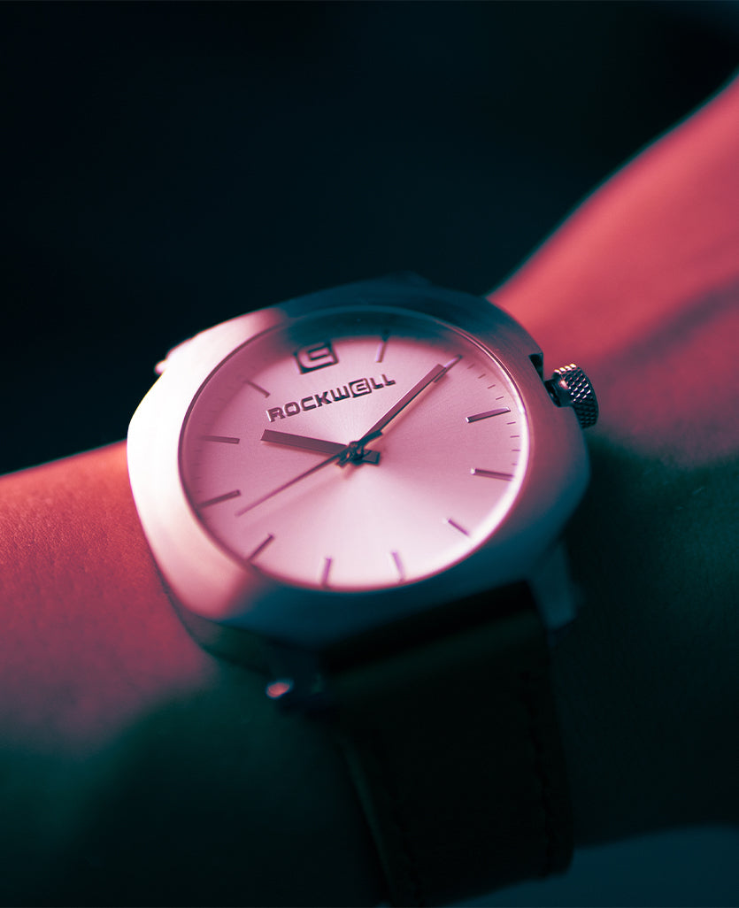 Pink dial silver watch with black strap on wrist