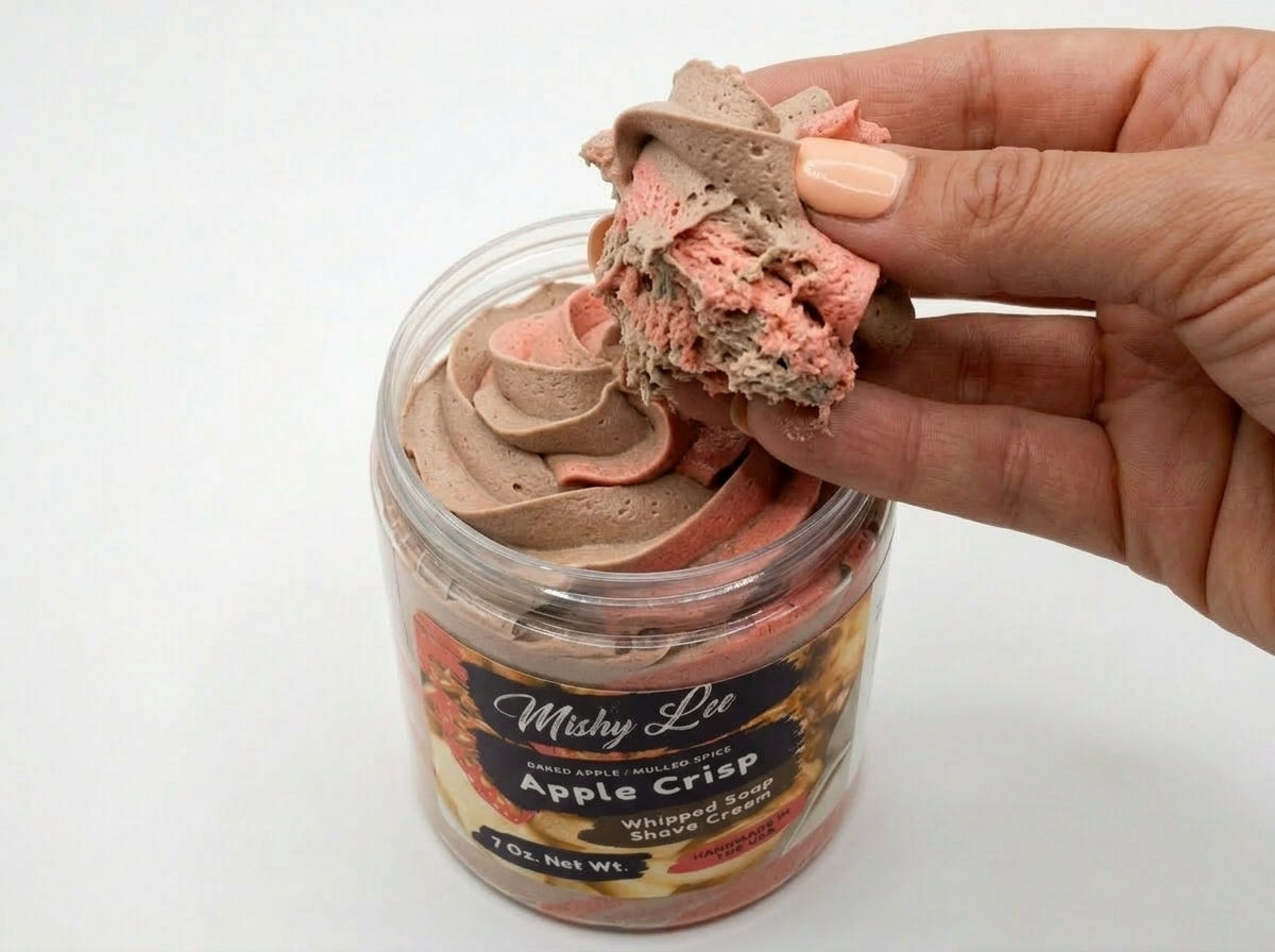 Whipped soap and shave cream scoop in hand, with pink and brown swirls