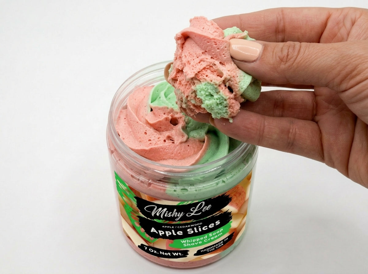 Hand holding a scoop of pink and green whipped soap, jar in view below
