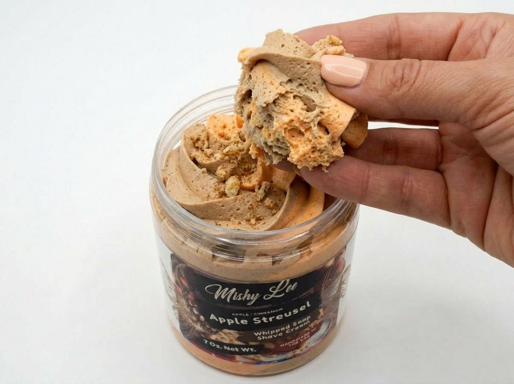 Hand scooping beige whipped soap and shave cream from clear jar