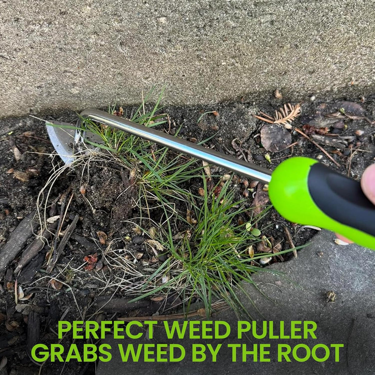 Garden weeder tool with green handle and three-prong metal head near weeds