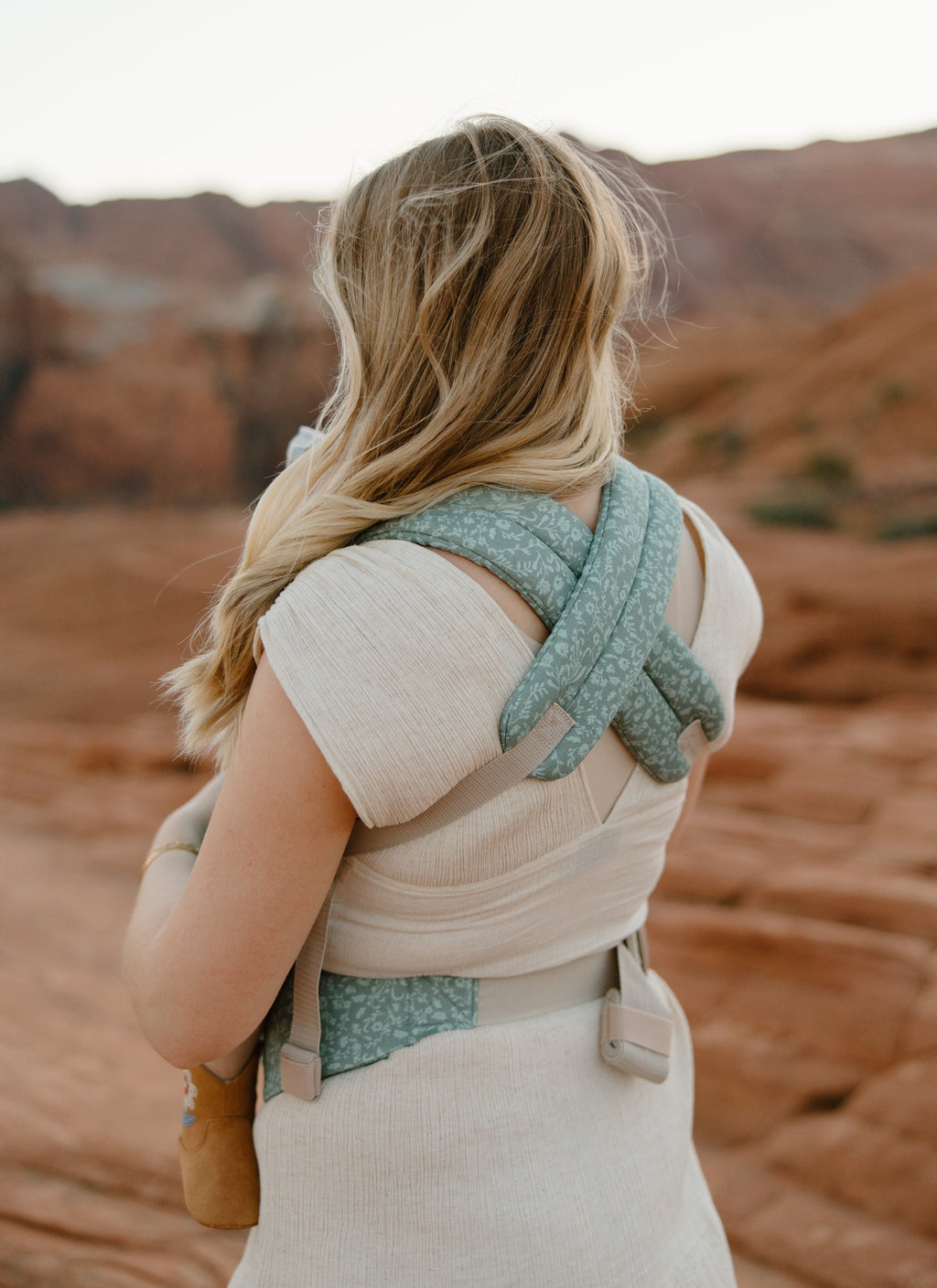 Teal floral baby carrier with pocket, back view showing carrying straps