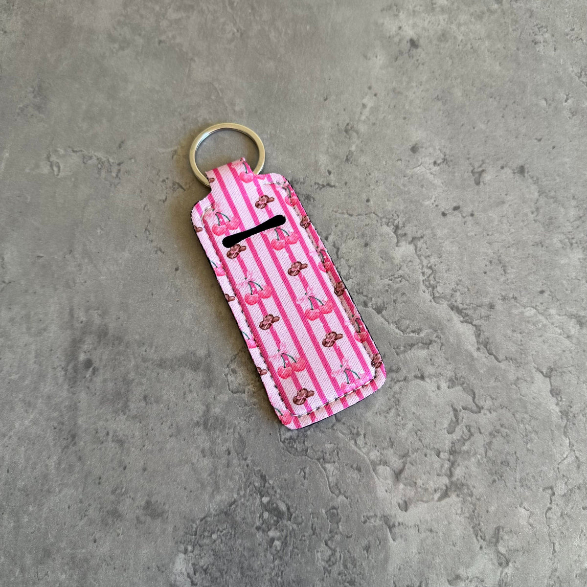 Pink striped chapstick holder keychain with cowboy silhouettes and gold-tone key ring