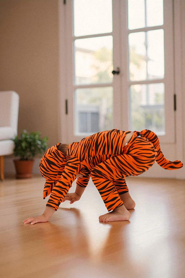 Orange tiger-print footed jumpsuit with hood and tail, baby crawling indoors