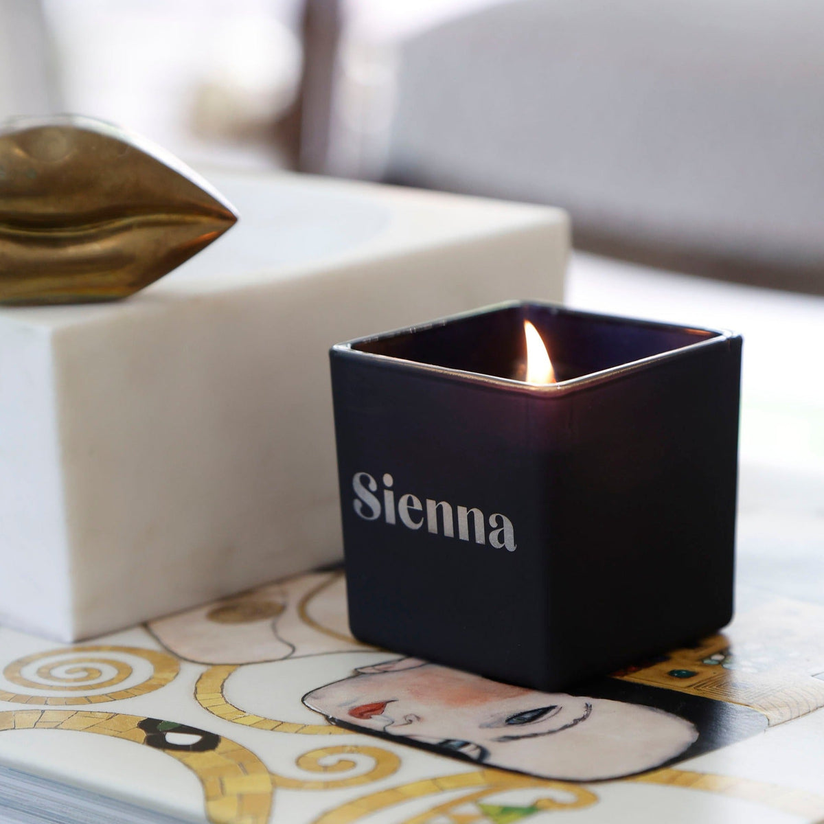 Lit dark engraved candle with Sienna name on front