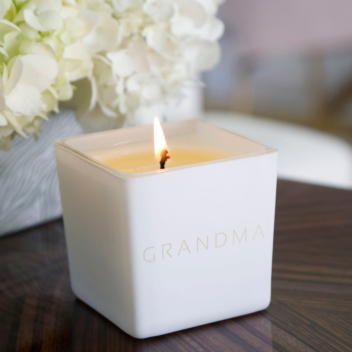 Lit white engraved candle jar with GRANDMA name in gold