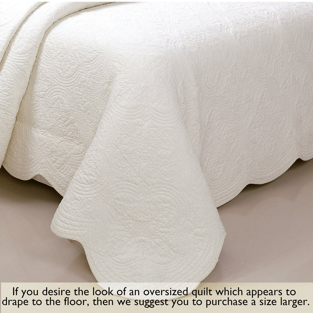 Ivory quilt draped on bed with embossed circular medallion fabric pattern