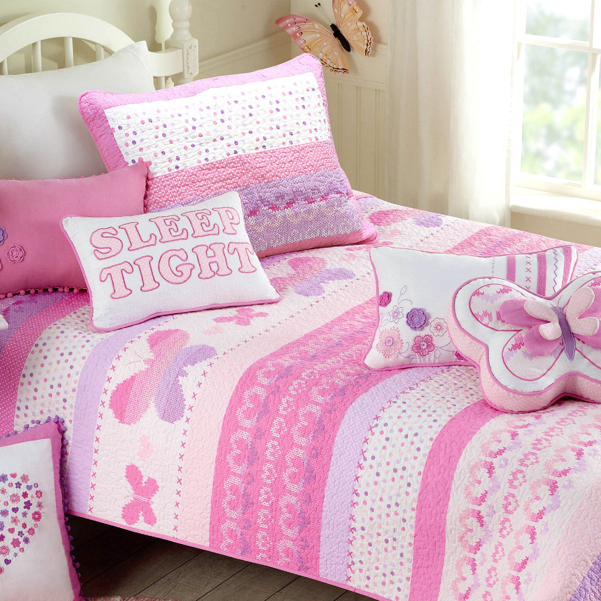 Pink and white reversible quilt bedding set with patterned pillow and butterfly accents