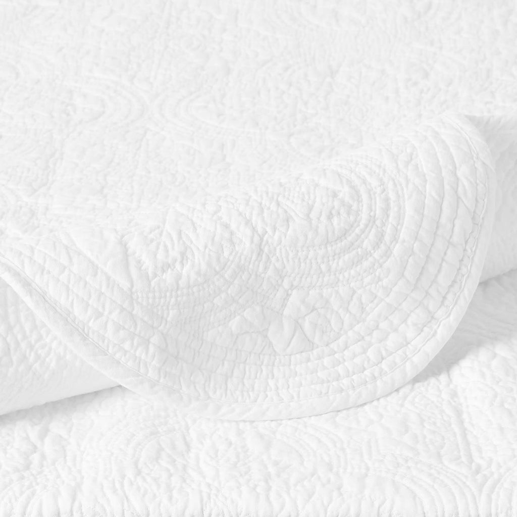 Close-up of white quilt with raised medallion quilting and stitched channel lines
