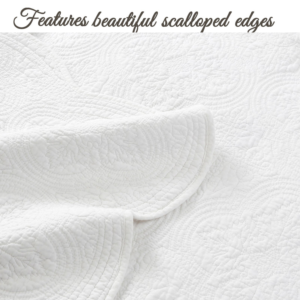 White quilt with scalloped edge trim and raised medallion quilt pattern