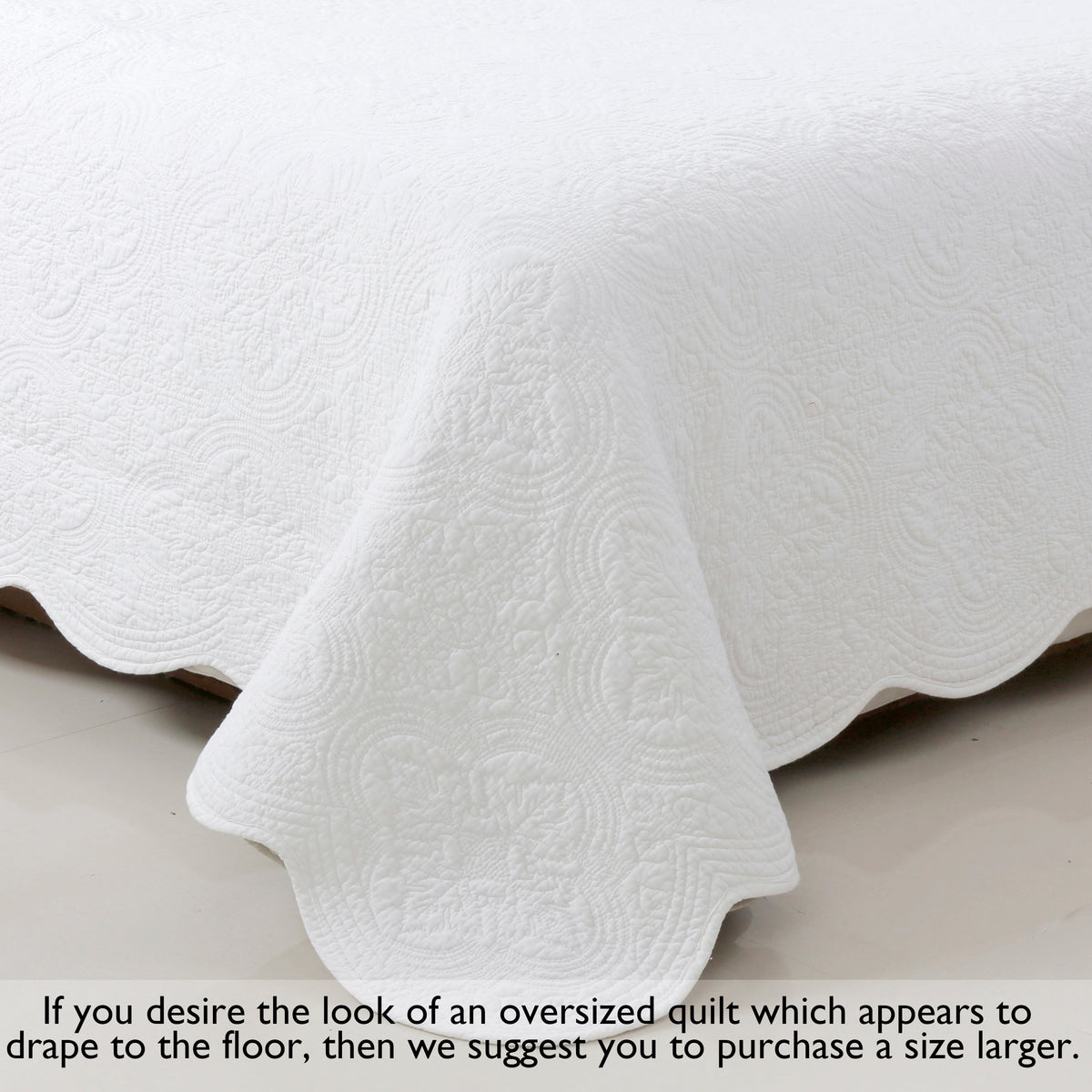 White quilt draped on bed with scalloped hem edge