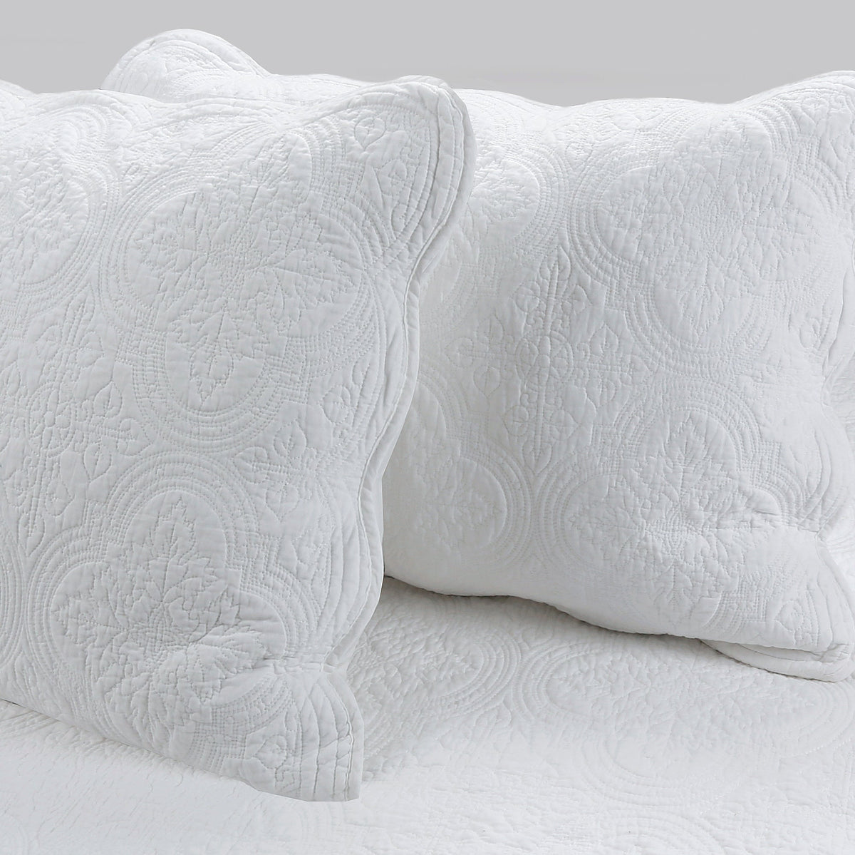 White quilted sham pillows with textured wave pattern on daybed
