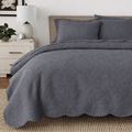 Gray quilt bedding set with reversible medallion quilting and scalloped bed skirt edge