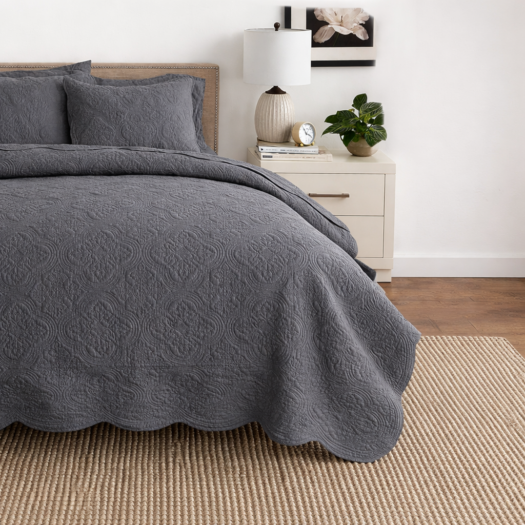 Gray reversible quilt bedding set with matching pillow on bed, scalloped hem