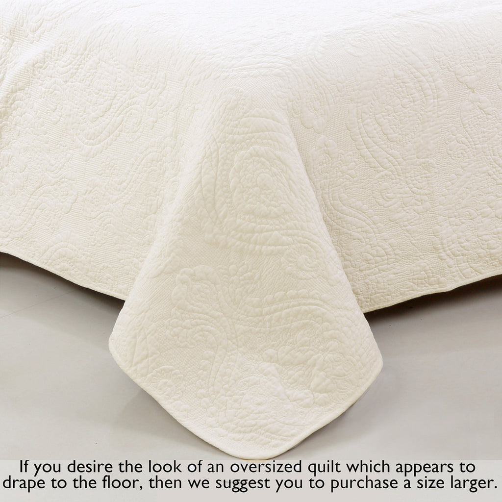 Ivory cotton quilt with detailed quilting and draped corner edge