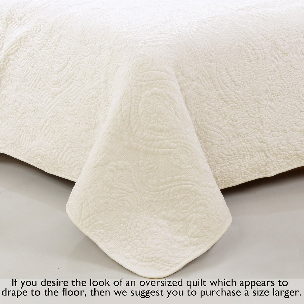 Ivory cotton quilt with detailed quilting and draped corner edge