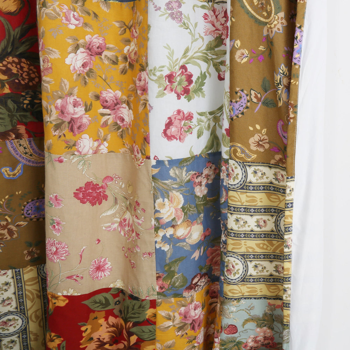 Close-up patchwork fabric with floral blooms, paisley stripes, and solid border trim