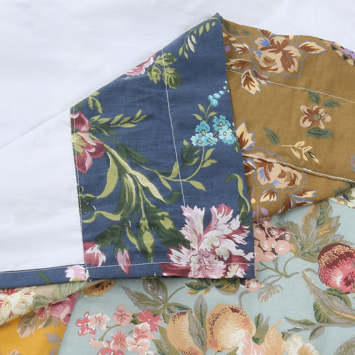 Patchwork quilt fabric detail with floral print squares in blue, tan, and pink