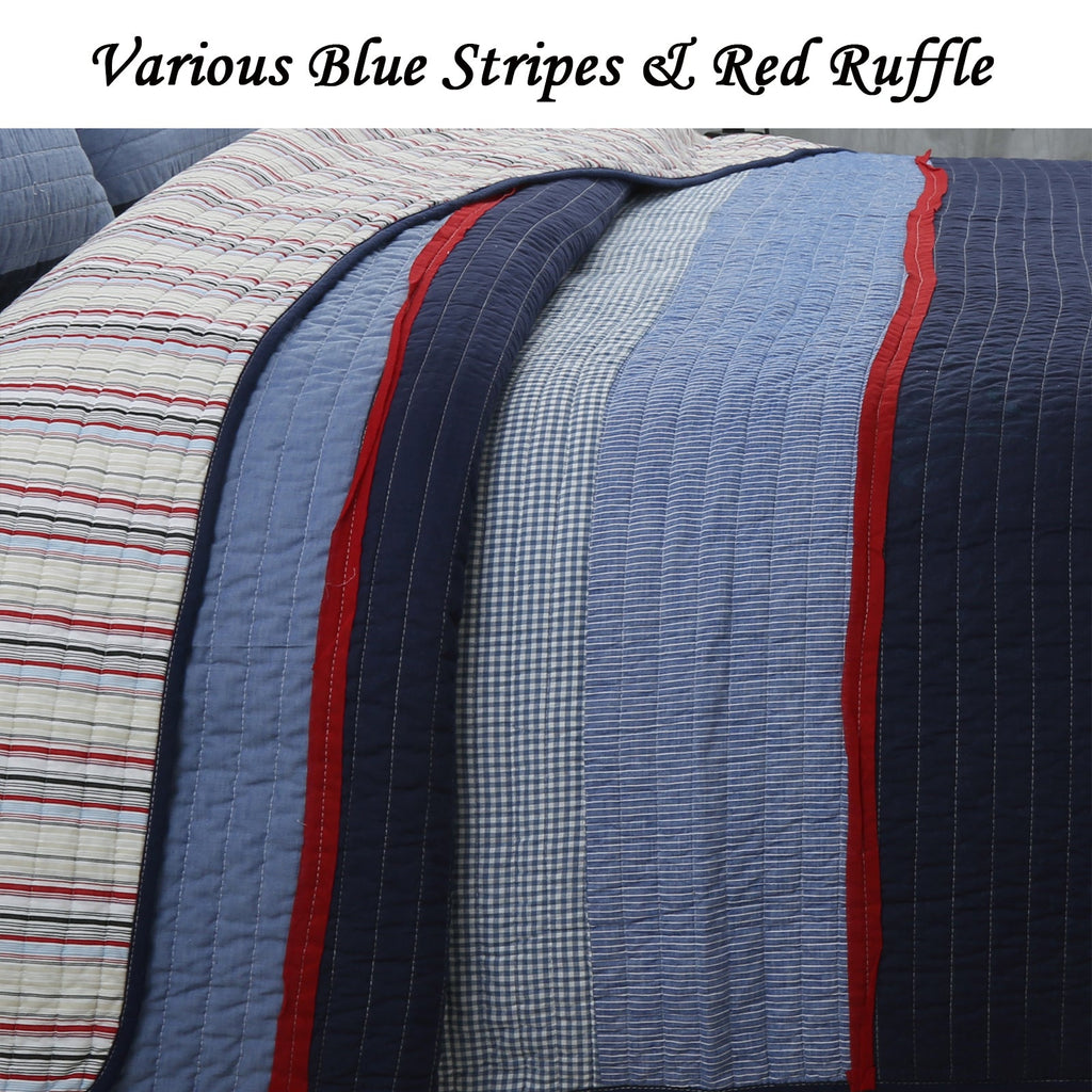 Reversible quilt with layered blue stripe panels, navy edge, and red ruffle trim