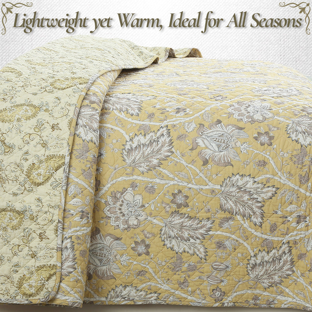 Light yellow and gray reversible quilt with dense floral quilting and draped edge