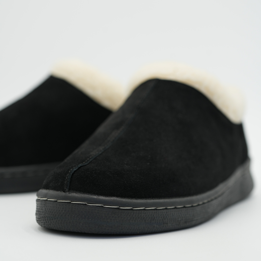 Close-up of men's black suede slipper with cream sherpa collar and tread sole