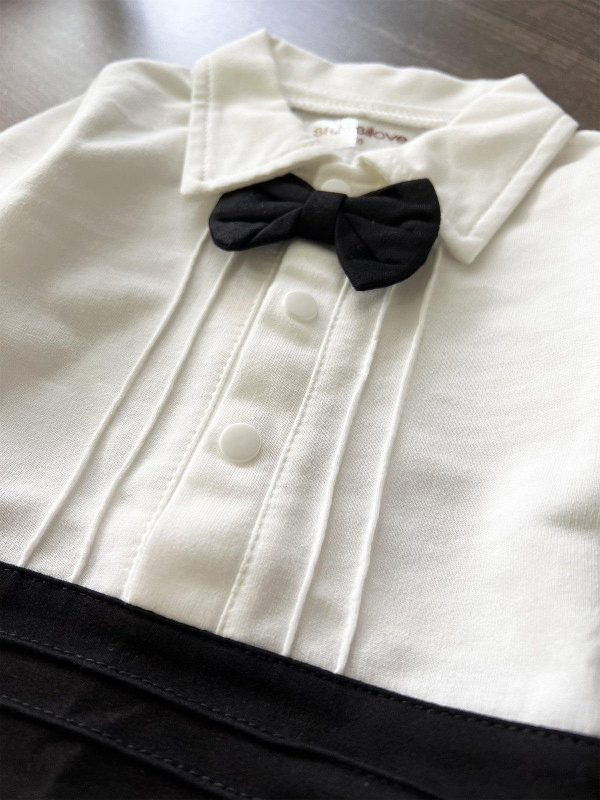Cream baby tuxedo shirt with black bow tie and vertical button placket