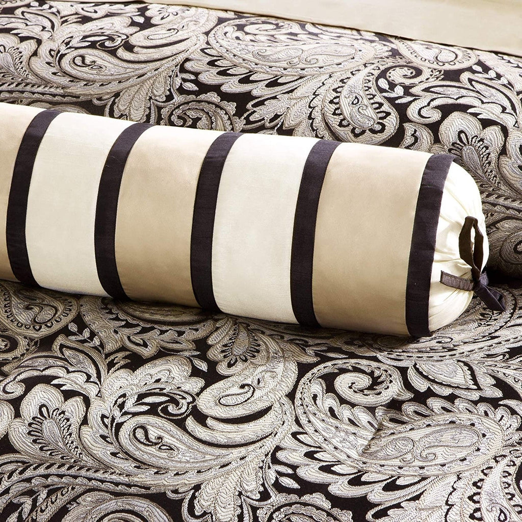 Cream and black striped bolster pillow on black-and-white paisley bedding