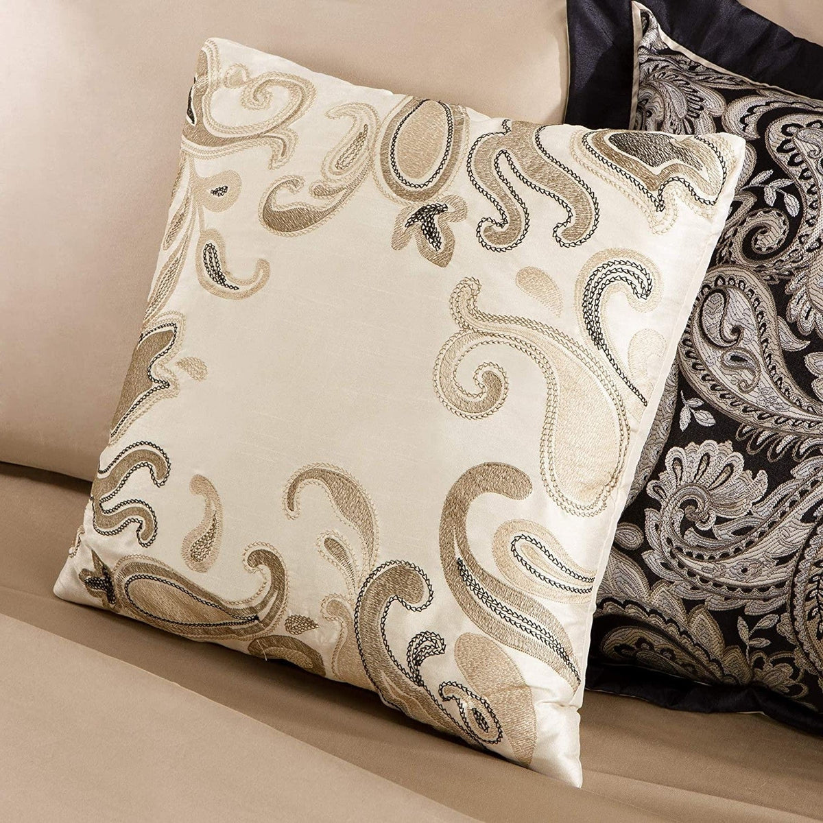 Beige accent pillow with tan paisley pattern beside black-and-white pillows