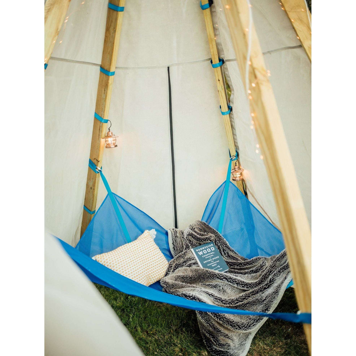 Inside view of canvas teepee tent with blue rope ties, storage pocket and blankets