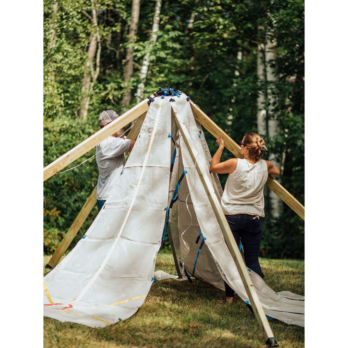Canvas teepee tent with wood poles and blue rope ties, side openings