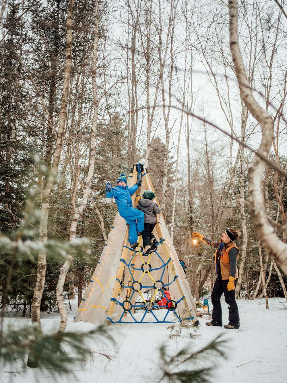 Solar string lights on a teepee tent in snowy woods with people nearby