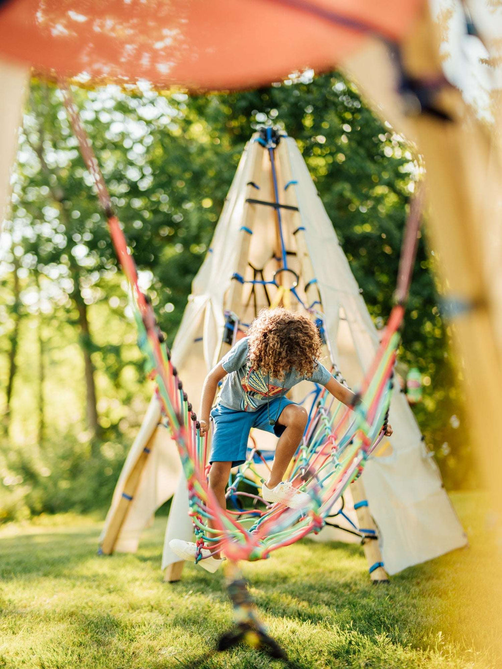 Rope suspension bridge hammock-style net with multicolor cords and children