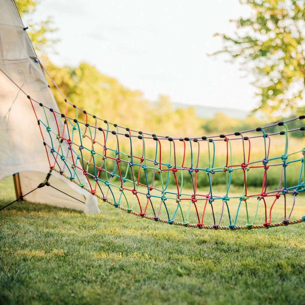 Multicolor rope suspension bridge with braided net and hanging side ropes