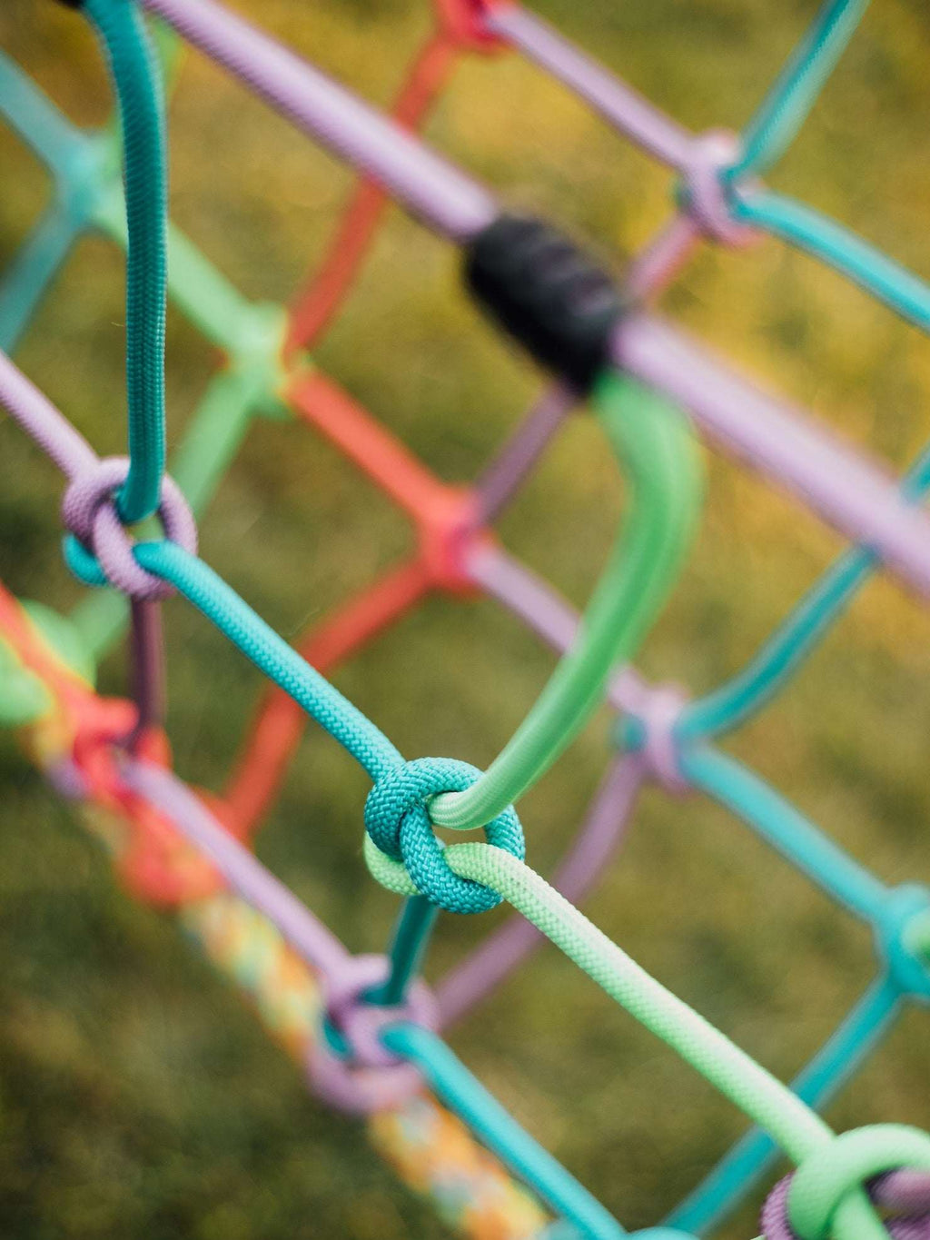 Close-up of multicolor braided rope knots on suspension bridge