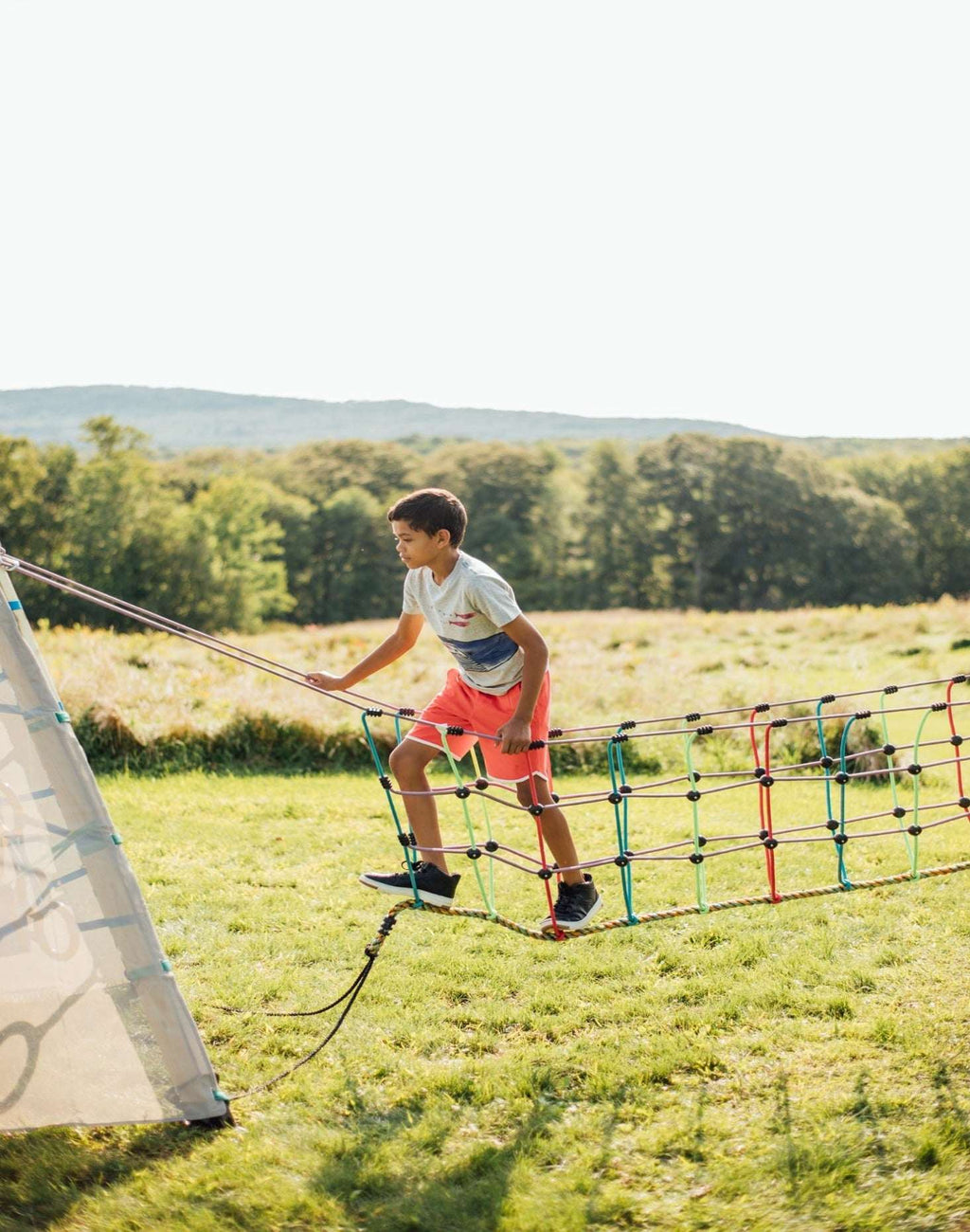 Rope suspension bridge with multicolor net and child climbing