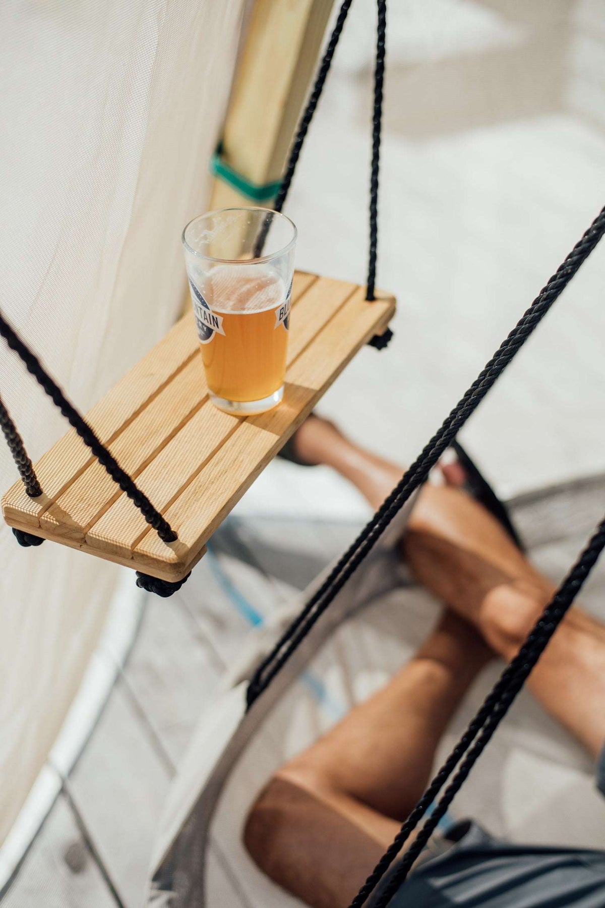 Bijou Rest hanging wooden swing seat with glass of drink, close-up