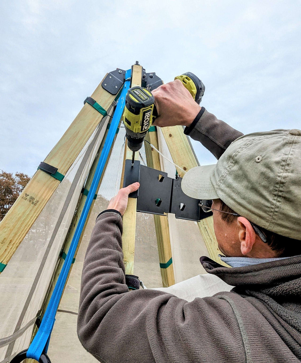 Hand installing a swing arm adaptor bracket onto a wooden playset beam