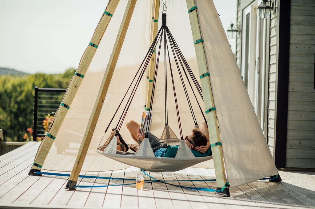 Off-white tipi play tent with hanging rope frame and hammock bed on patio