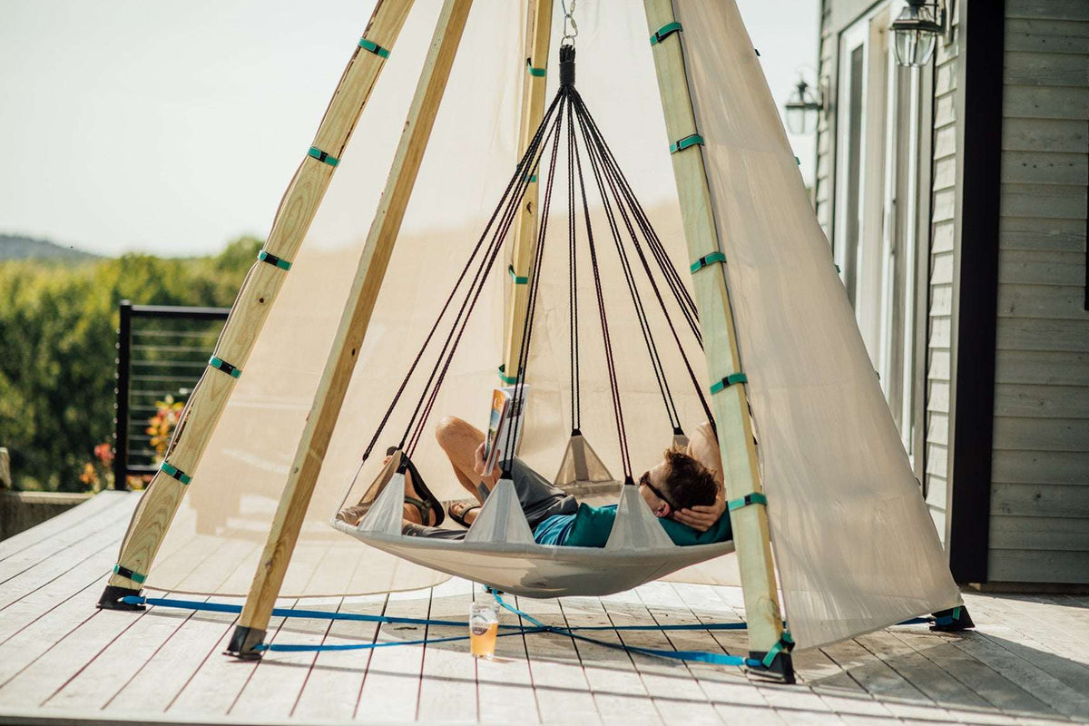 Off-white tipi play tent with hanging rope frame and hammock bed on patio