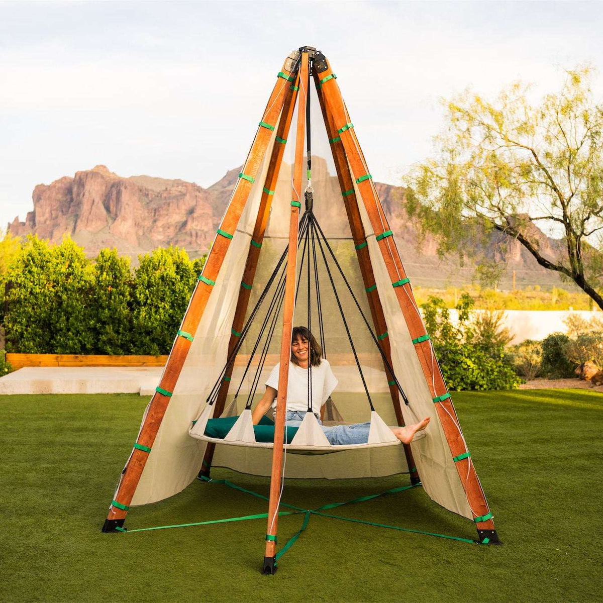 Tipi-style play tent with off-white canvas, colorful pole wraps, and rope hammock