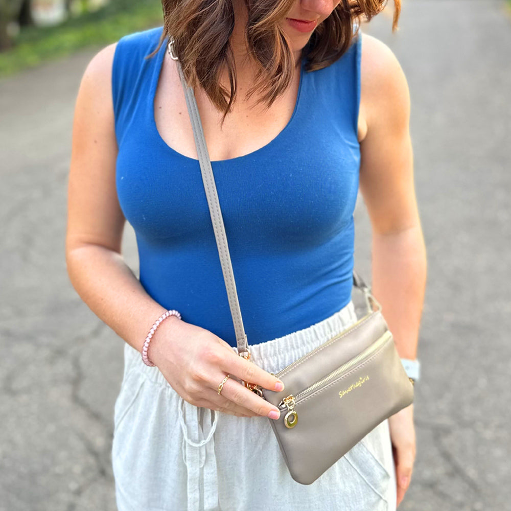 Taupe crossbody RFID wallet worn across body with gold-tone hardware