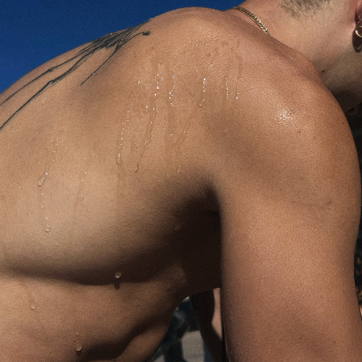Perfume droplets on bare shoulder skin with subtle shimmer