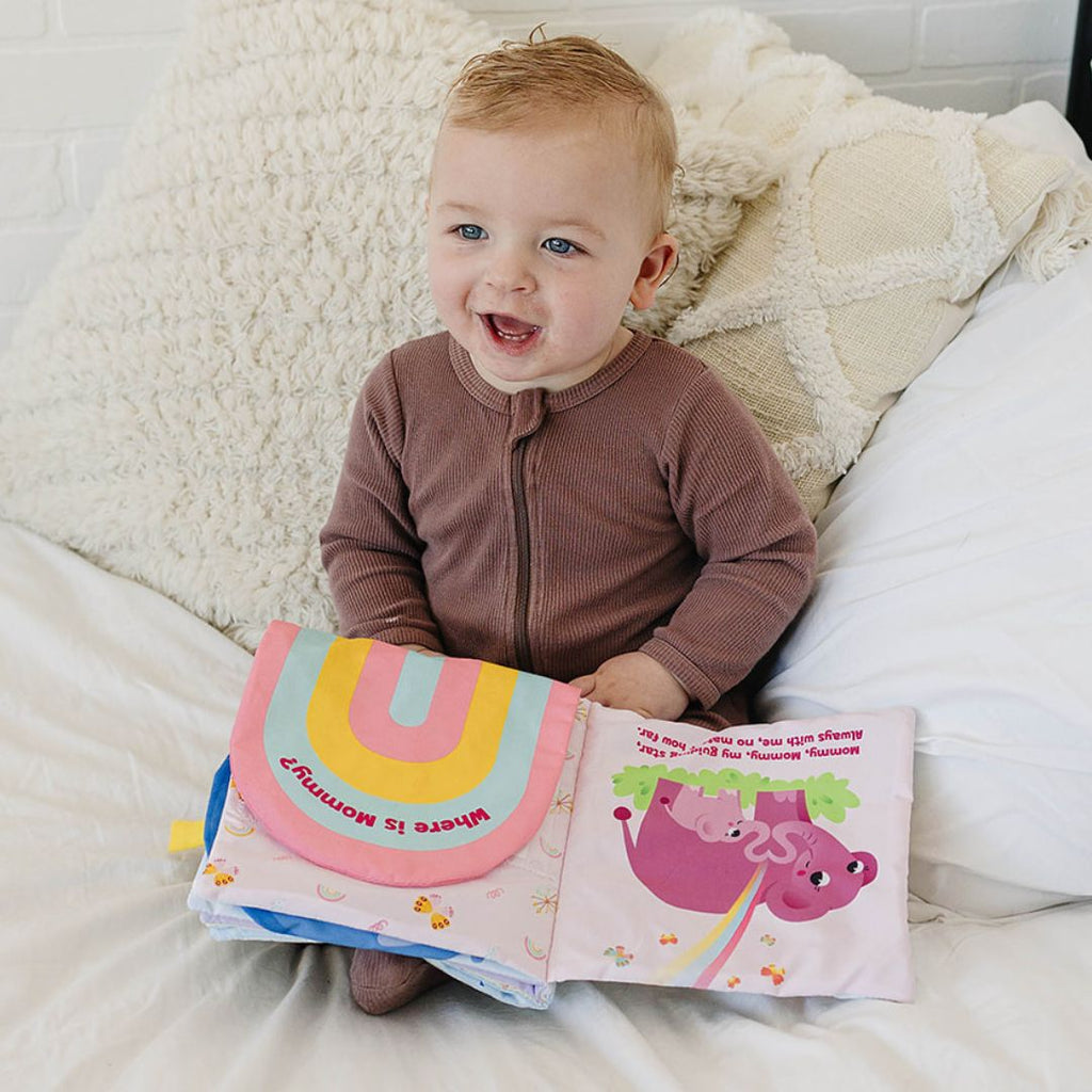 Toddler holding a pink photo-pocket storybook album with dinosaur illustration