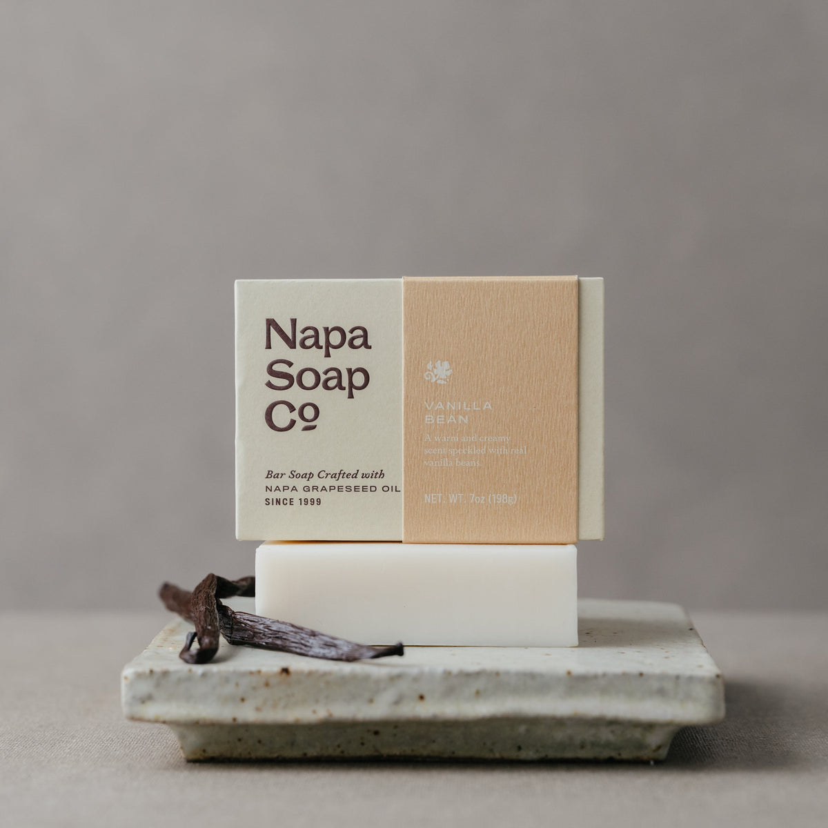 Vanilla bar soap with visible bar on stone tray, with white and kraft-brown boxes