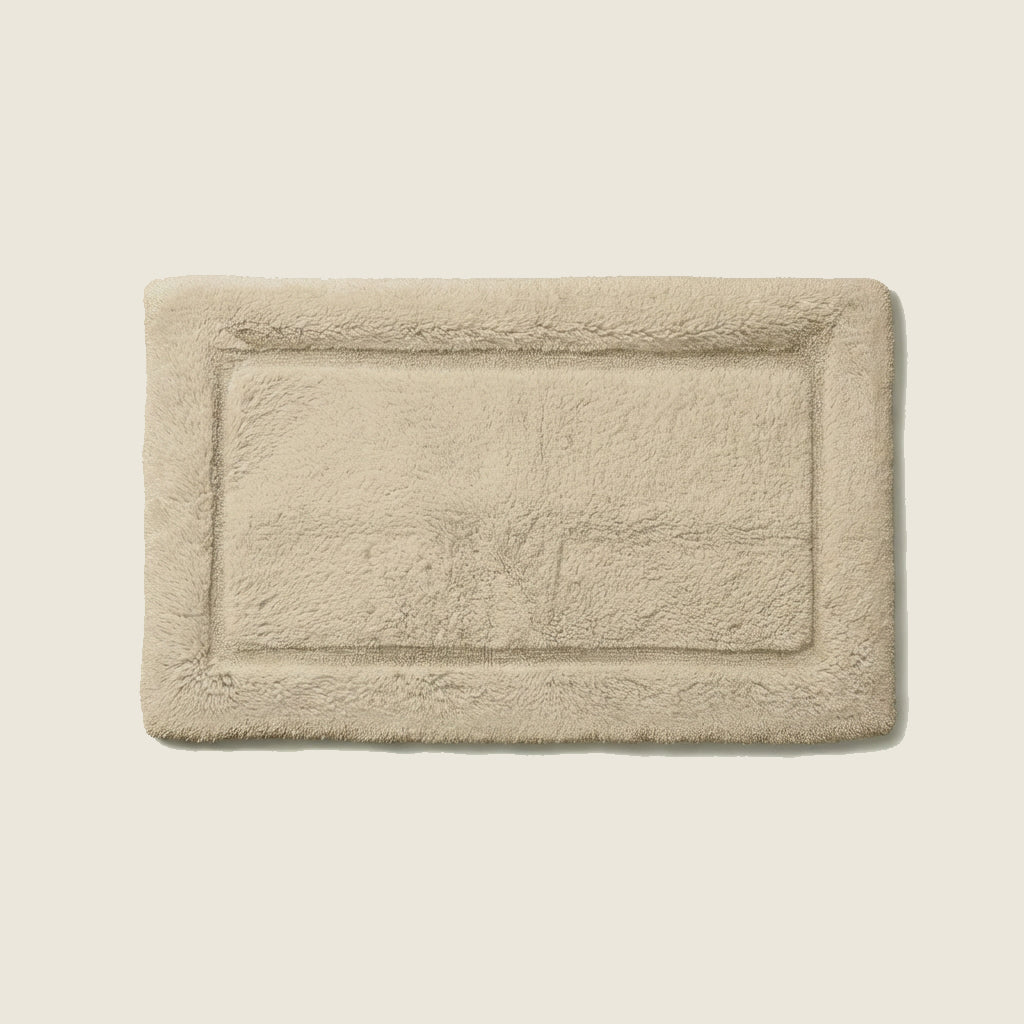 Sand beige plush bath mat with raised rectangular border