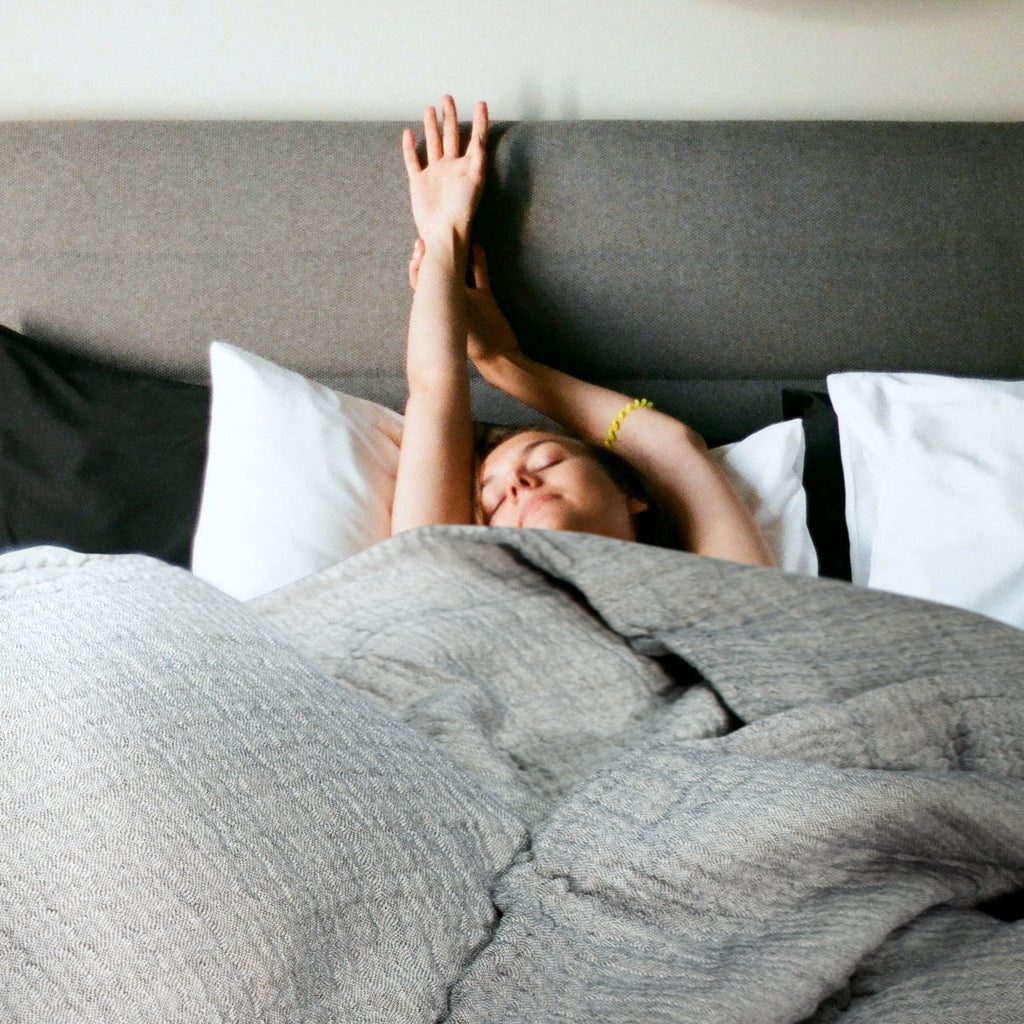 Grey muslin coverlet on a bed with reversible textured folds and soft drape