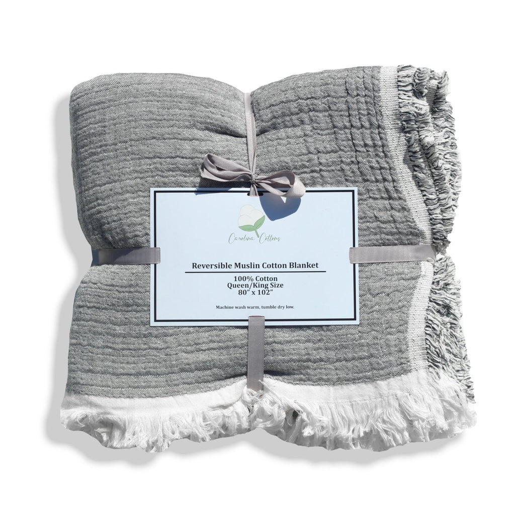 Reversible muslin cotton coverlet folded in grey with fringed edge detail
